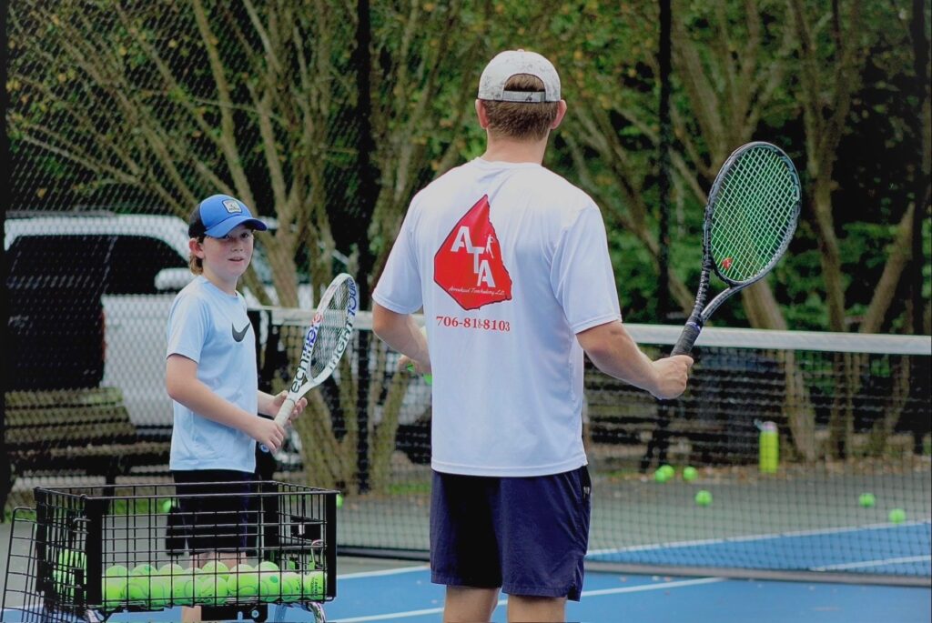 An ATA coach working one-on-one with a junior player on court