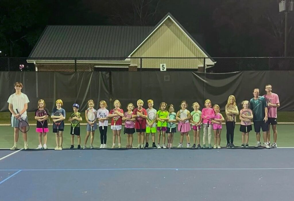 Junior clinic players lined up with their coaches under the lights