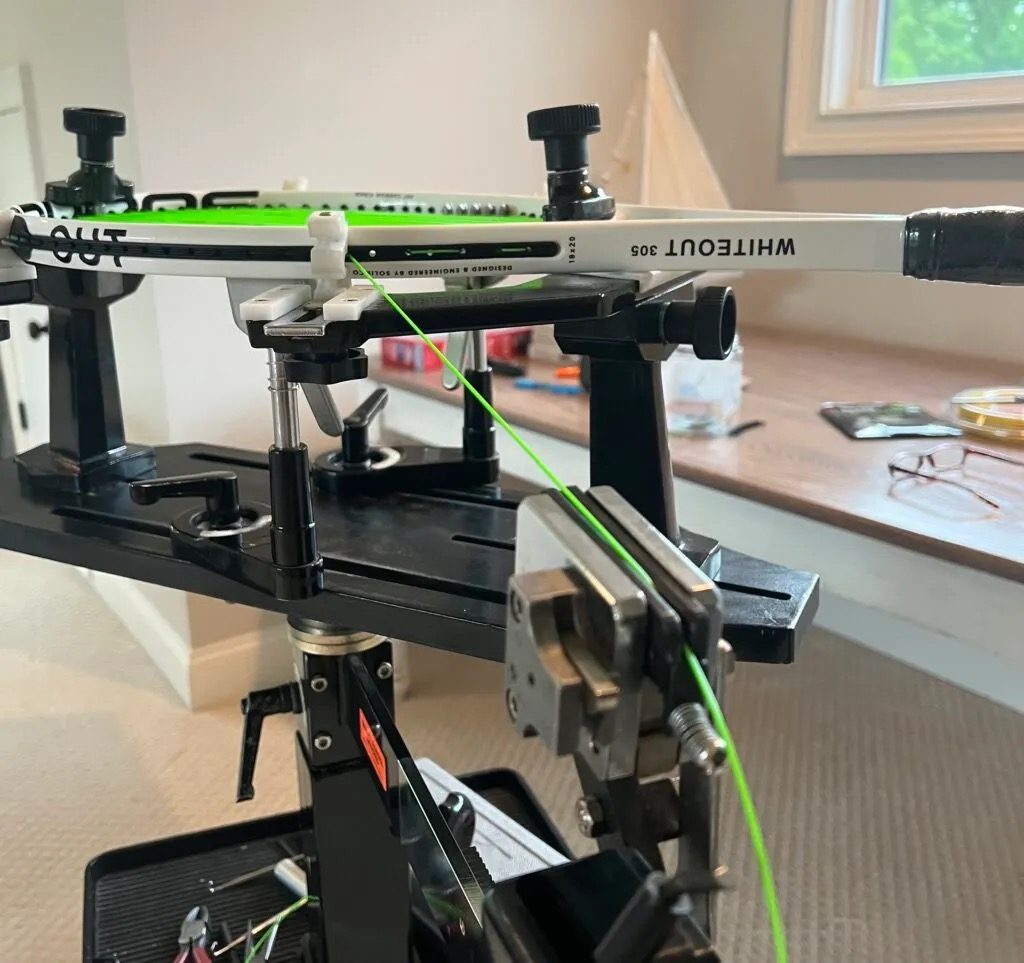 A white racket clamped in a stringing machine